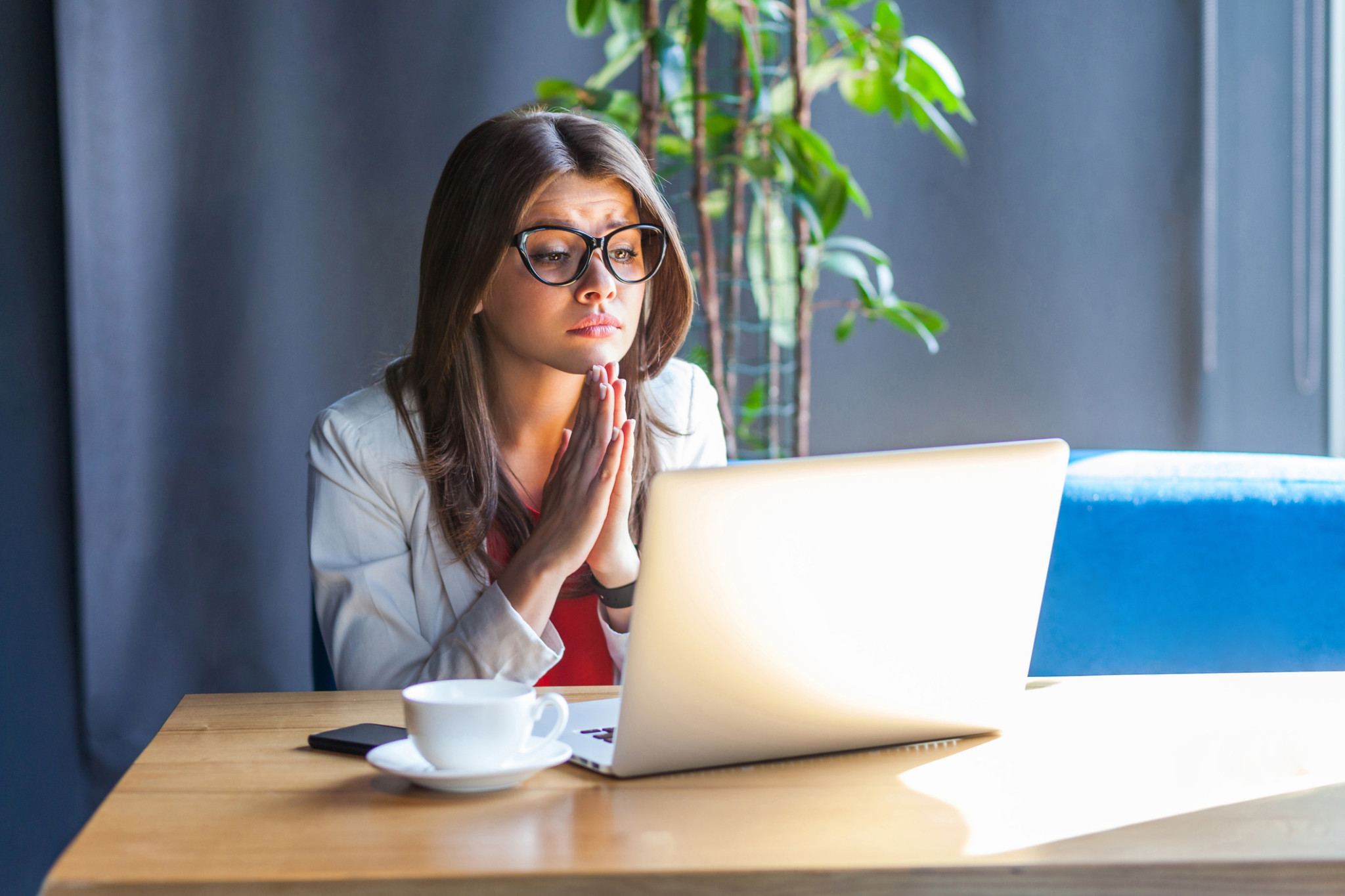 Portrait of hopeful beautiful stylish brunette young woman in glasses sitting, looking at her laptop monitor with worry face and begging or pleading | Need insurance now