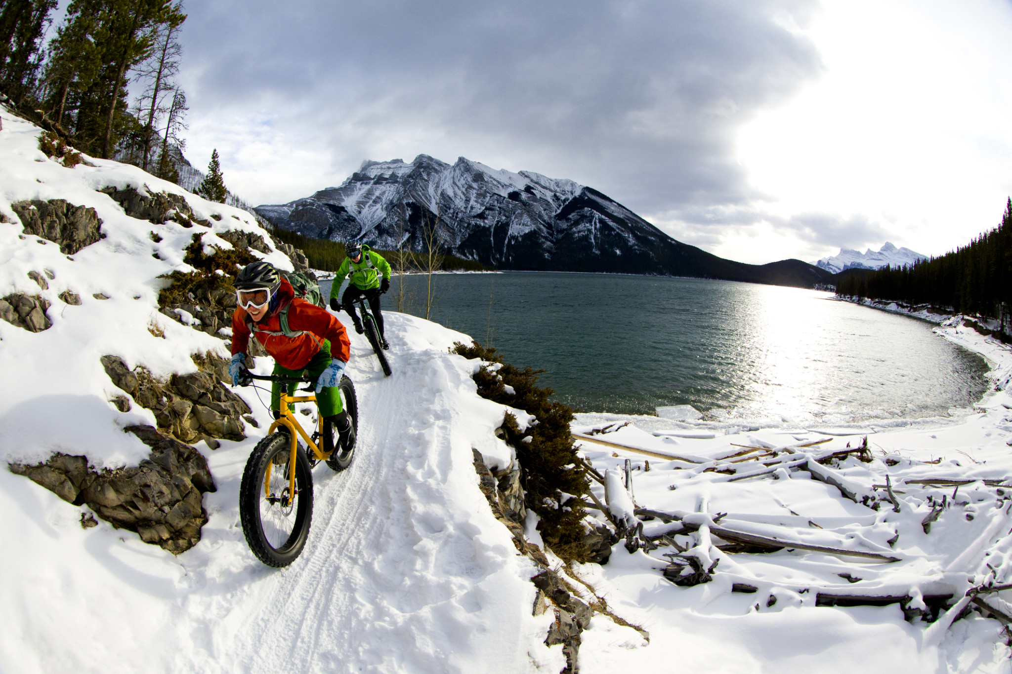 two people cycling on snowy mountain path