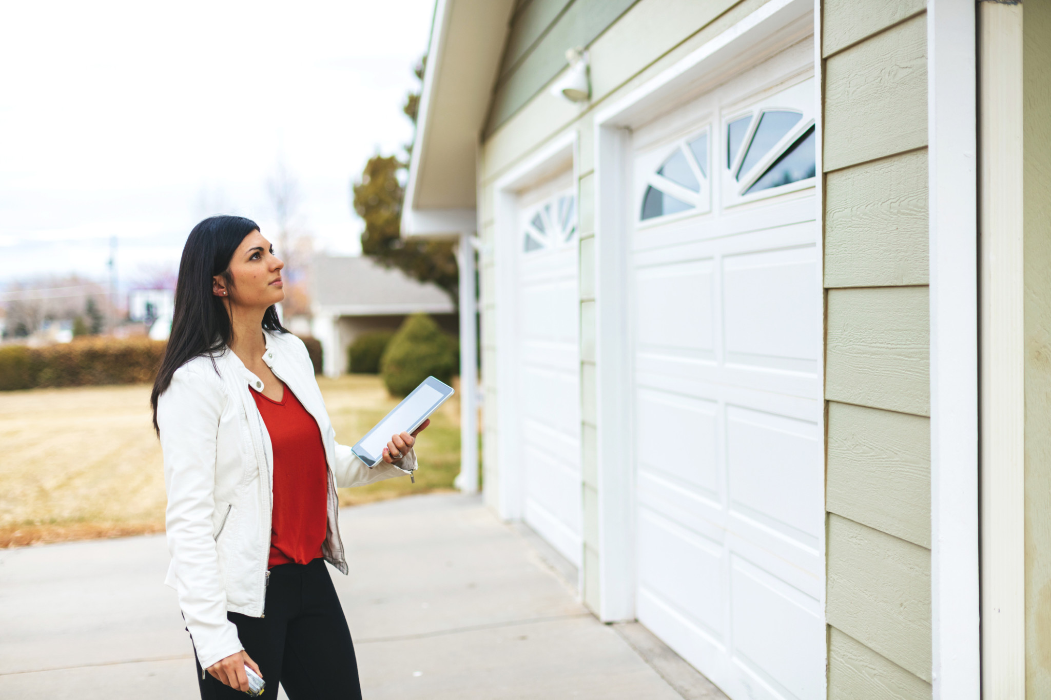 woman standing in front of home garage with tablet